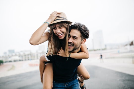 Spain, Barcelona, young man giving his girlfriend a piggyback ride