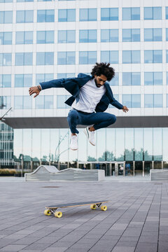 Spain, Barcelona, young businessman doing skateboard tricks in the city