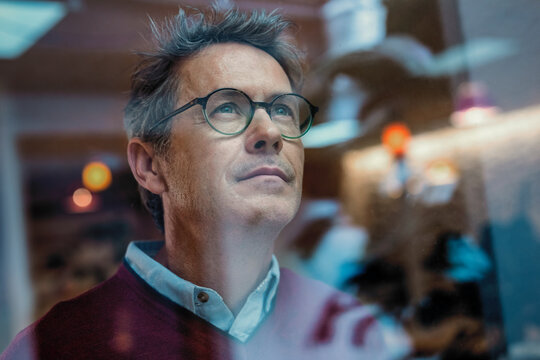 Contemplative architect looking through window at office