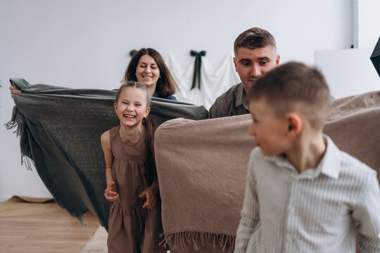 Happy family enjoying quality time playing with blankets indoors