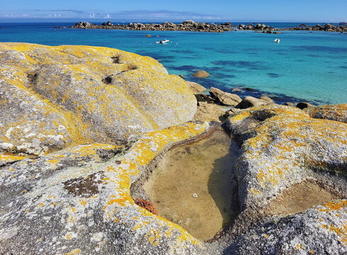 Die K&uuml;ste am Plage de Roc'h ar Gonc beeindruckt mit gelb leuchtenden Flechten auf den Granitfelsen und kleinen Gezeitent&uuml;mpeln vor dem t&uuml;rkisblauen Meer.