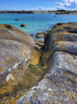 Die K&uuml;ste am Plage de Roc'h ar Gonc beeindruckt mit gelb leuchtenden Flechten auf den Granitfelsen und kleinen Gezeitent&uuml;mpeln vor dem t&uuml;rkisblauen Meer.