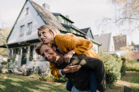 Man giving his wife a piggyback ride in garden