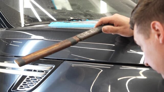 PDR. Paintless Car Dent Repair. Process of paintless dent repair on car body. The mechanic at the auto shop with tools to repair dents in car body. Body repair. A specialist repairs a dent on the car.
