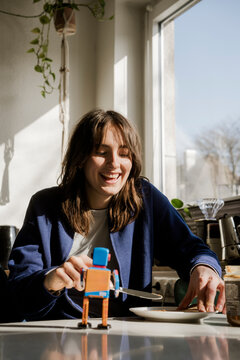 Student smiling during breakfast with a toy robot at home