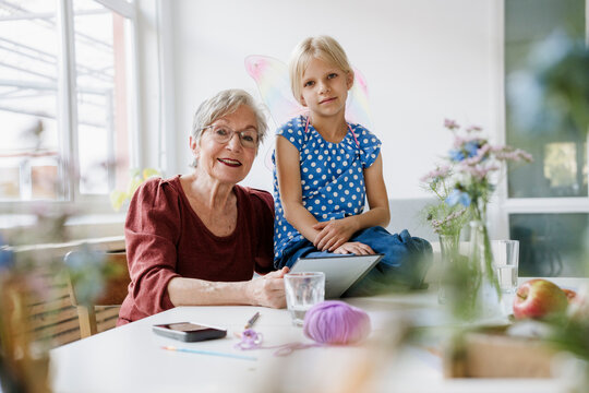 Smiling grandmother and grandchild playing with tablet at home