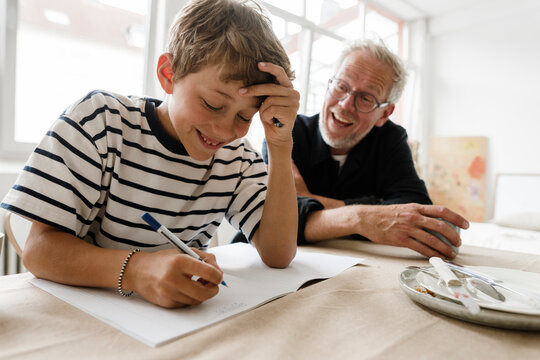 Smiling father helping son with homework at home