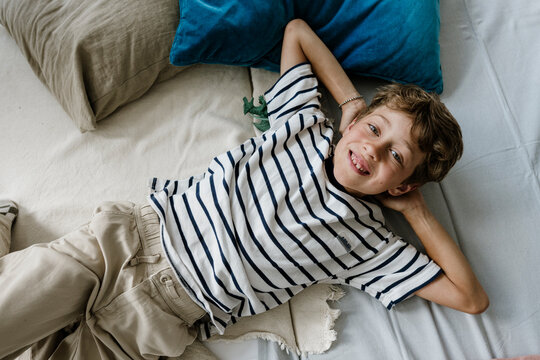 Smiling boy relaxing on a bed looking at camera