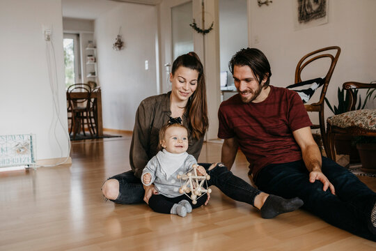 Happy family with baby girl sitting on the floor at home