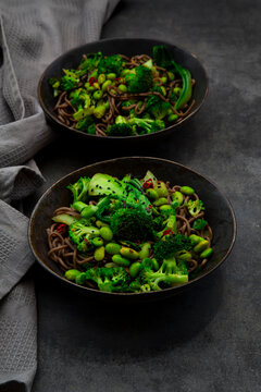 Soba noodle bowl with broccoli pak choi and edamame on dark table