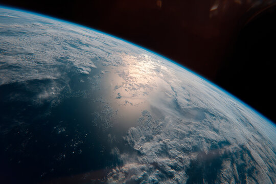 Sunlit Earth surface and cloud formations viewed from orbital altitude