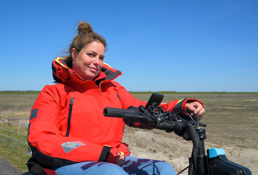Wheelchair user in red jacket exploring Terschelling waddensea island