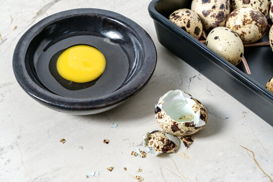 Close up of cracked quail eggshell with yolk beside fresh quail eggs
