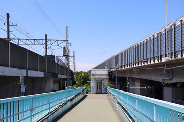 線路と高速道路に挟まれた歩道橋とエレベーターの風景  © 茂明 北村