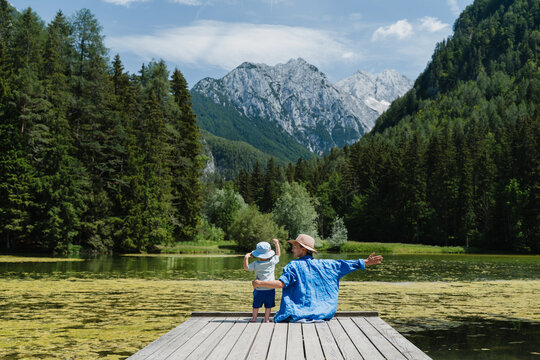 Woman and child on pier enjoying mountain lake during family vacation