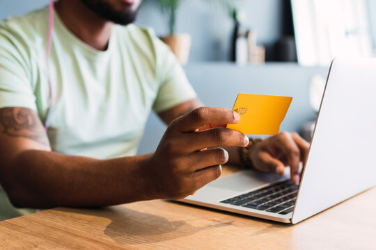 Man holding credit card by laptop in desk at home