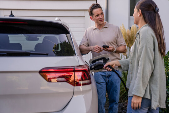 Family charging electric car at home demonstrating sustainability