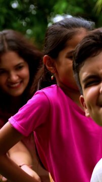 Indian family playing tug of war rassi khech in home garden, spending quality fun time together enjoying outdoor sports, cheerful Asian parents children bonding through traditional backyard activity