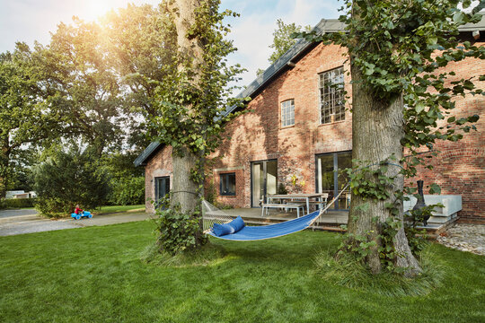 Residential house with hammock in garden and girl playing in background