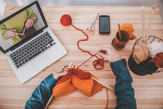 Knitting man using laptop for watching online tutorial, partial view