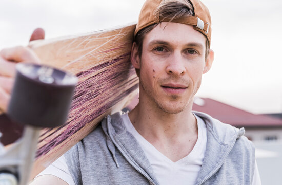 Portrait of man carrying skateboard