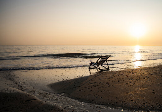 Empty deckchair on a peaceful sandy beach at sunset