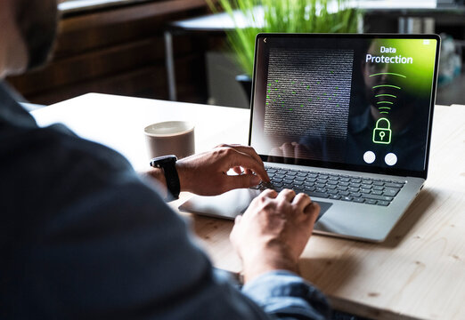 Typing on laptop with data protection screen at office desk