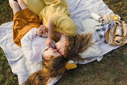 Mother and daughter rubbing noses and lying on picnic blanket