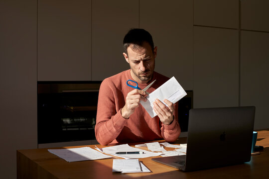 Man opening envelope with scissors at home