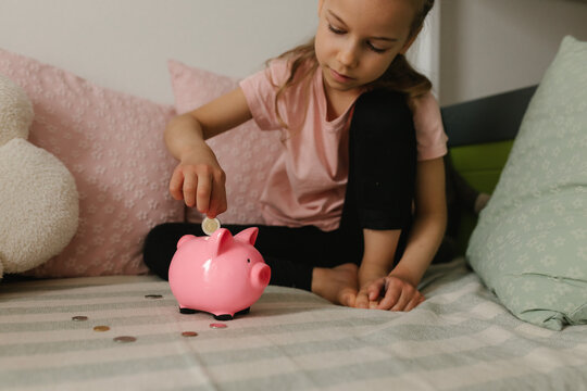 Girl putting coin into pink piggy bank for future planning