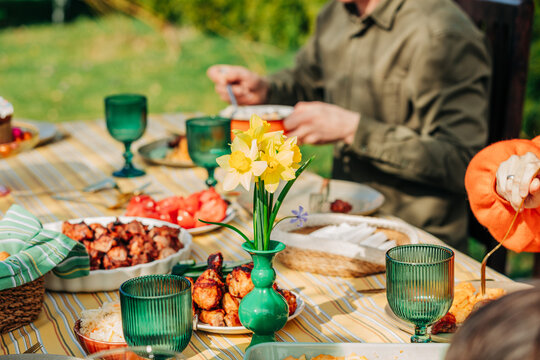 Family eating festive Easter dinner together in sunny backyard