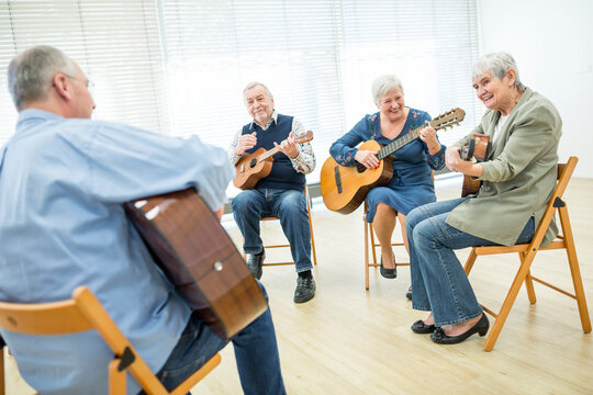 Seniors in retirement home attending guitar class, making music