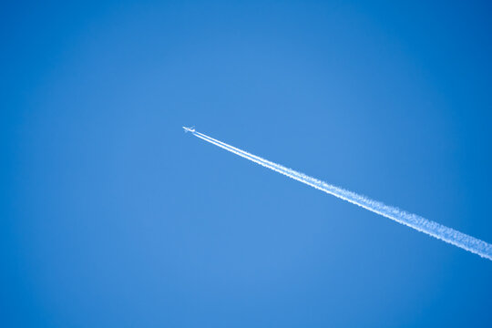 twin engined jet liner aircraft with contrails, in flight at high altitude, clear blue sky