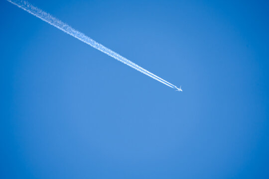 twin engined jet liner aircraft with contrails, in flight at high altitude, clear blue sky