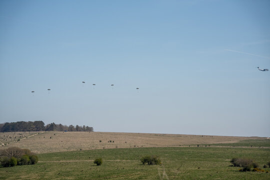 a large grey cargo plane dropping low level parachute cargo