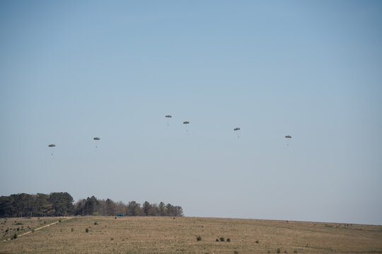 a large grey cargo plane dropping low level parachute cargo