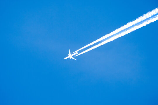 twin engined jet liner aircraft with contrails, in flight at high altitude, clear blue sky