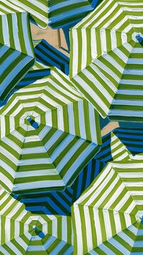 Parasols ray&eacute;s verts et blancs vus du dessus cr&eacute;ant un motif g&eacute;om&eacute;trique