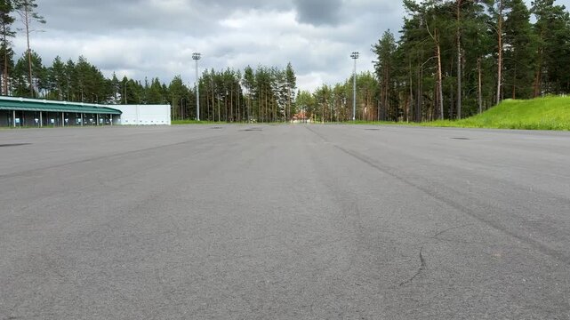Roller skating training on a wide asphalt sports ground, an open sports area near a pine forest under an overcast sky
