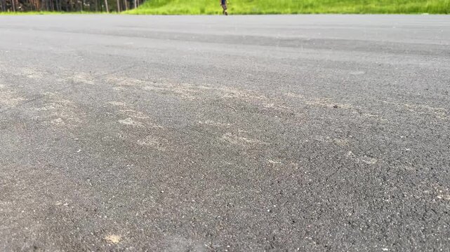A gentle asphalt concrete section on an outdoor sports training ground, a man on roller skates