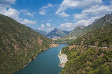 Fototapeta premium Scenic view of the turquoise Lake Koman winding through the rugged mountains of Albania