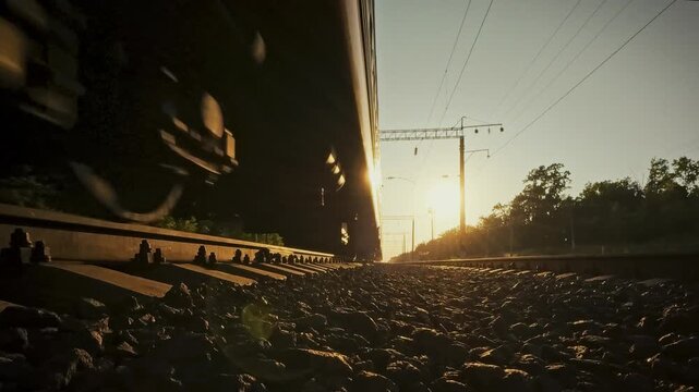 In bright sunlight, close-up captures freight train's wheelsets flashing over rails, highlighting fast rail transport and the robust infrastructure that powers modern freight delivery on the network