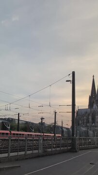 Train departs from Cologne Central Station in Germany during the evening hours with buildings in the background