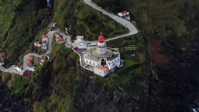 Stunning aerial perspective of the historic Ponta do Arnel Lighthouse perched on a rugged cliffside overlooking the Atlantic Ocean in Portugal