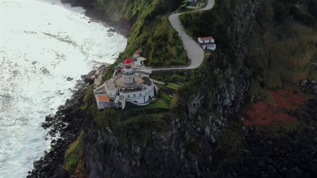 Stunning aerial view of the Ponta do Arnel Lighthouse, situated on a dramatic cliffside overlooking the Atlantic Ocean in Azores, Portugal