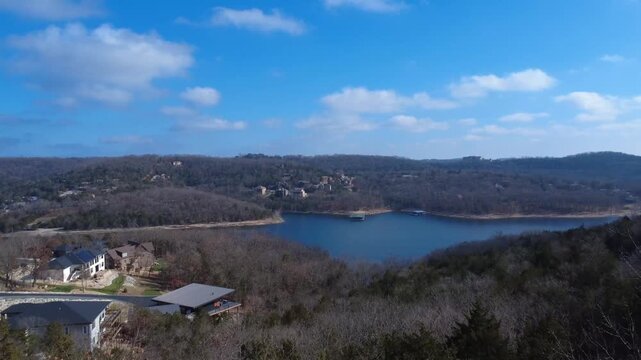 A sweeping aerial view reveals a peaceful lake surrounded by rolling Ozark hills and dense forest.