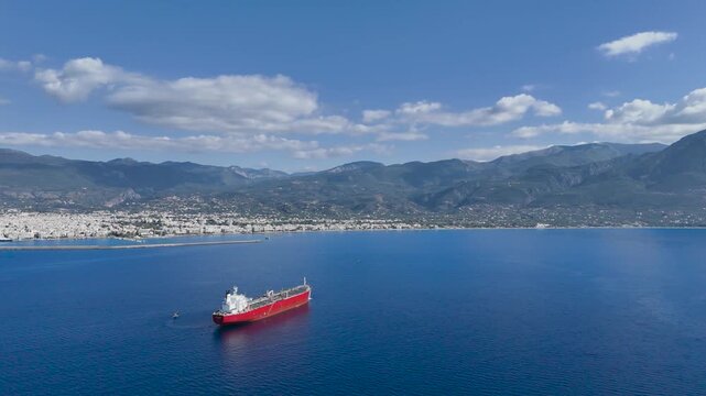 Aerial View of Red Cargo Ship Anchored Near Kalamata Harbor with Taygetus Mountains and Coastal Cityscape, Messinian Gulf, Peloponnese Greece