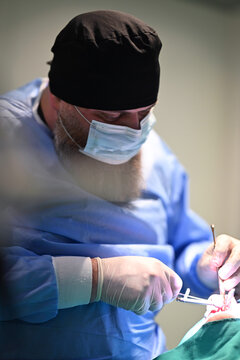 Surgeon Performing Precise Surgical Procedure in Operating Room Wearing Mask and Protective Gear