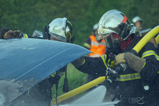 Firefighters operating water hose during car accident rescue training exercise