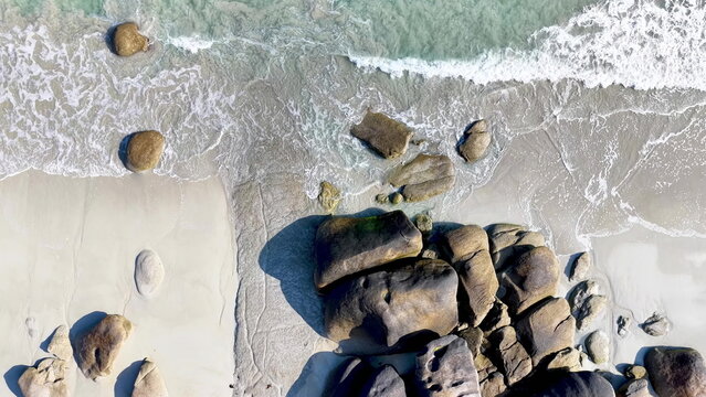 Spektakul&auml;re Drohnenaufnahme vom Plage de Boutrouilles: Wellen treffen auf feinen Sandstrand und imposante, runde Granitfelsen an der wilden K&uuml;ste der bretonischen Region.